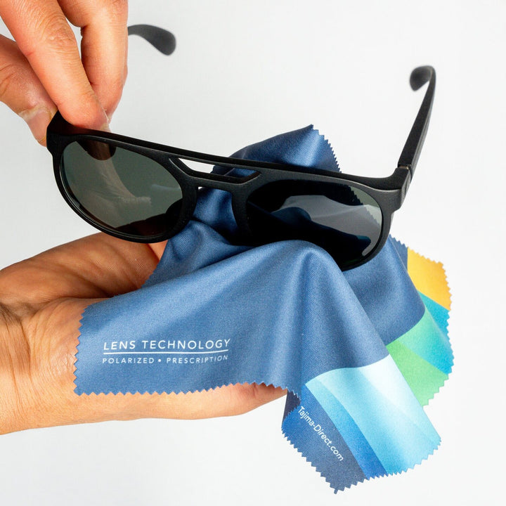 Hand holding sunglasses wrapped in Tajima microfiber cleaning cloth demonstrating use to clean lenses