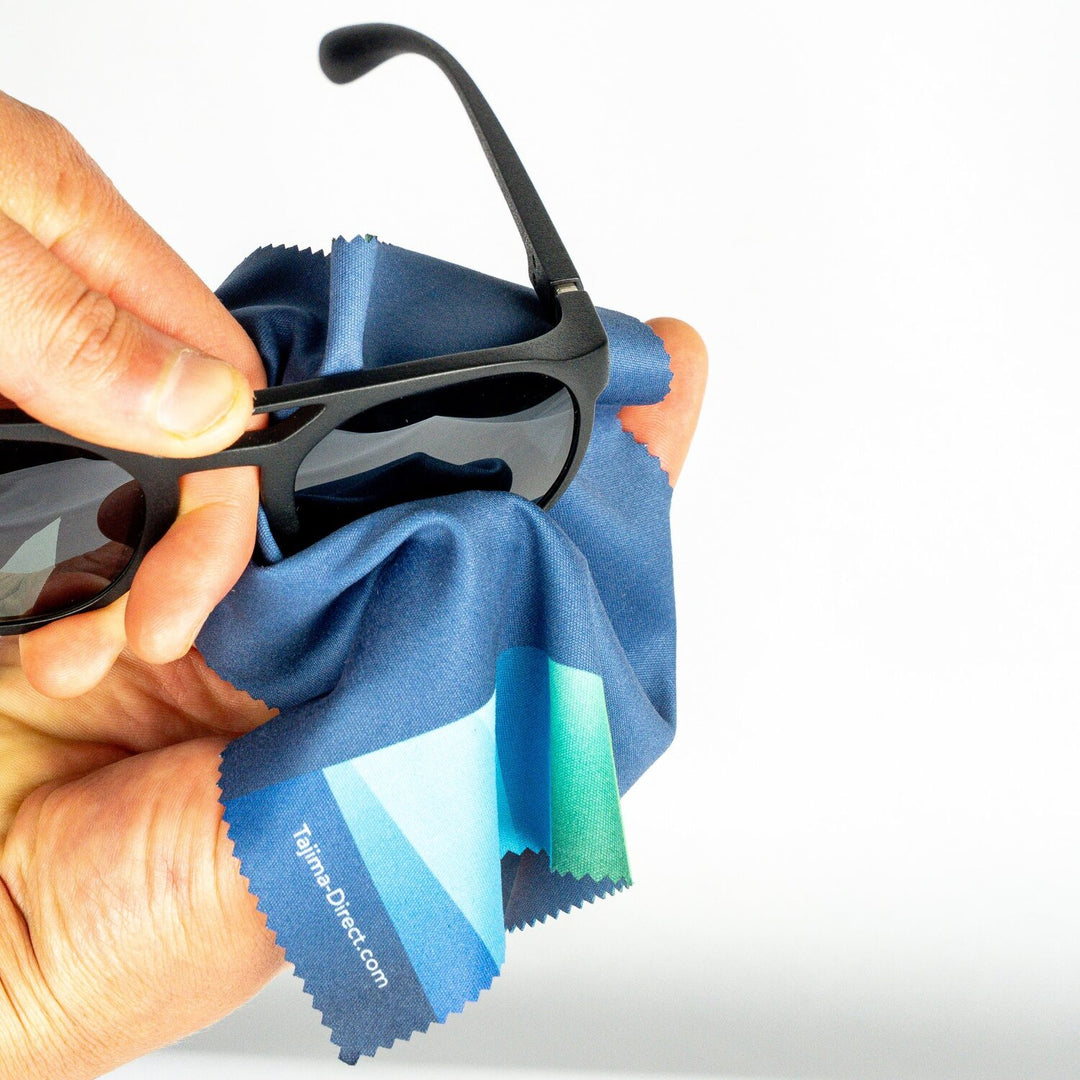 Close-up of sunglasses being cleaned with Tajima branded microfiber cloth