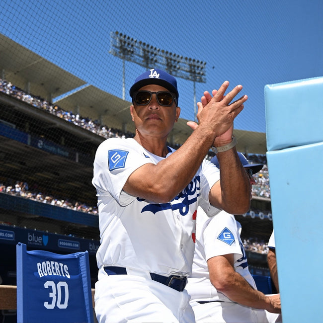 Dave Roberts in basn5 sunglasses applauding at Dodger Stadium
